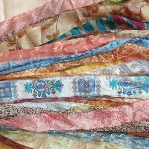 May include: A collection of colorful silk fabric scraps in various patterns and textures. The fabric scraps are arranged in a layered, cascading design, creating a visually appealing and textured display.