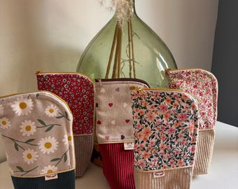 May include: A collection of five upright fabric pouches featuring a two-tone design. Each pouch combines a patterned upper section with a solid-coloured, ribbed lower section. The patterns include white daisies, red floral, hearts, and pink flowers.