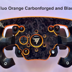 Puede incluir: Un volante de carreras negro y naranja flúor con un diseño de fibra de carbono. El volante tiene múltiples botones y un logotipo central. El texto "Fluo Orange Carbonforged and Black" está en la parte superior de la imagen.