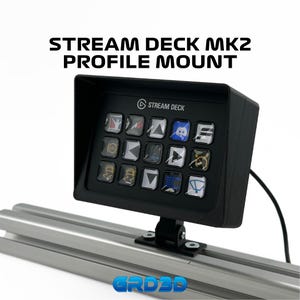 May include: A black Stream Deck MK2 profile mount with a black Stream Deck attached to it. The Stream Deck has a variety of buttons with different icons on them. The mount is attached to a silver metal track.
