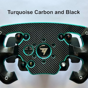 Pode incluir: Um volante de corrida preto e turquesa com um centro de fibra de carbono. O volante tem vários botões e um logótipo central. O texto "Turquoise Carbon and Black" está acima do volante.
