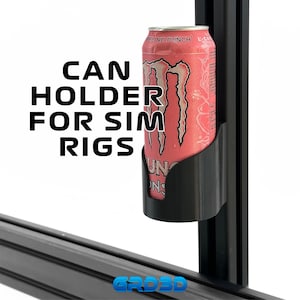 May include: A black can holder for sim rigs, holding a pink Monster energy drink can. The text "CAN HOLDER FOR SIM RIGS" is printed in large, bold, black letters. The can is held in place by a black plastic holder.