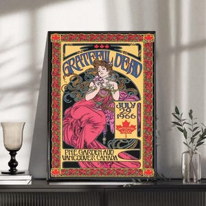 Puede incluir: Un póster enmarcado con un diseño vintage para un concierto de Grateful Dead en Vancouver, Canadá, el 29 de julio de 1966. La obra de arte incluye una mujer con un vestido rosa, detalles florales y el nombre de la banda en azul.