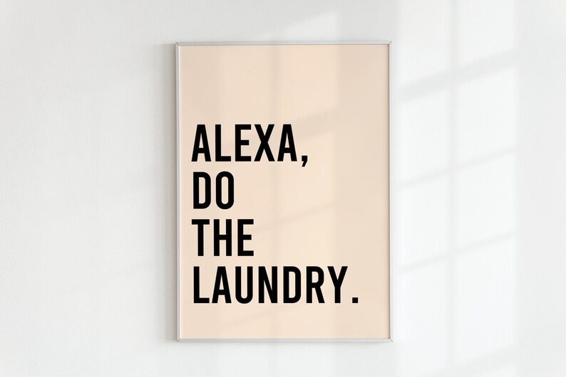 May include: A framed print with a light peach background and black text that reads "ALEXA, DO THE LAUNDRY."
