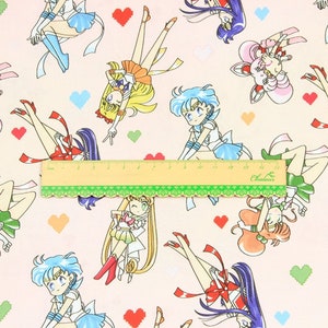 May include: A pink fabric with a repeating pattern of Sailor Moon characters. The characters are in various poses and are wearing their signature outfits. The background is a light pink with small hearts.