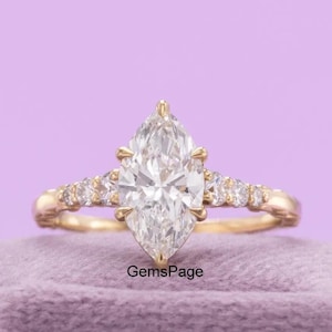 May include: A gold engagement ring with a marquise-cut diamond as the centerpiece. The band is adorned with smaller diamonds. The ring is displayed on a purple velvet surface against a lavender background. The text "GemsPage" is visible.