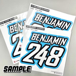 Può includere: Tre adesivi personalizzati per numeri di gara da 15,24 cm con il nome "Benjamin" e il numero "248" in bianco su sfondo azzurro chiaro. Gli adesivi sono lucidi e opachi.
