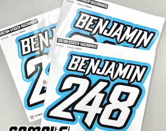 May include: Three 6-inch custom race number stickers with the name "Benjamin" and the number "248" in white on a light blue background. The stickers are glossy and matte.