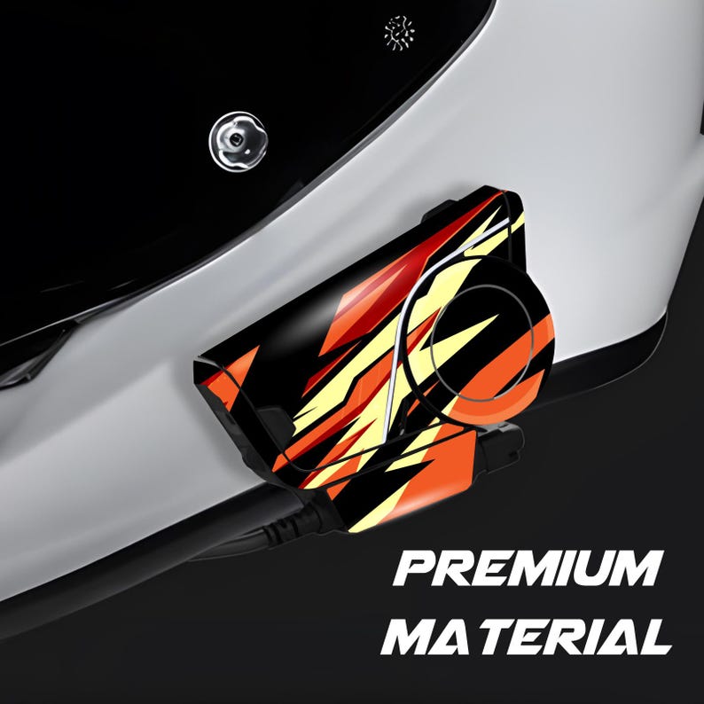 May include: Close-up of a black and white motorcycle helmet with a black, orange, and yellow patterned accessory attached. The text "PREMIUM MATERIAL" is visible in white at the bottom of the image.