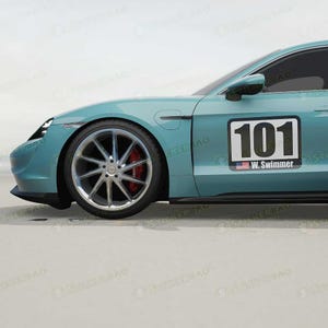 Könnte beinhalten: Ein türkisblauer Sportwagen mit einem schwarzen Rennnummernaufkleber an der Seite. Der Aufkleber zeigt "101" mit einer kleinen amerikanischen Flagge und dem Text "W. Swimmer" darunter.
