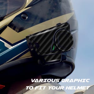 May include: A black and gray motorcycle helmet with a carbon fiber patterned communication device attached. The device has a circular control and a green indicator light. Text at the bottom reads "VARIOUS GRAPHIC TO FIT YOUR HELMET."