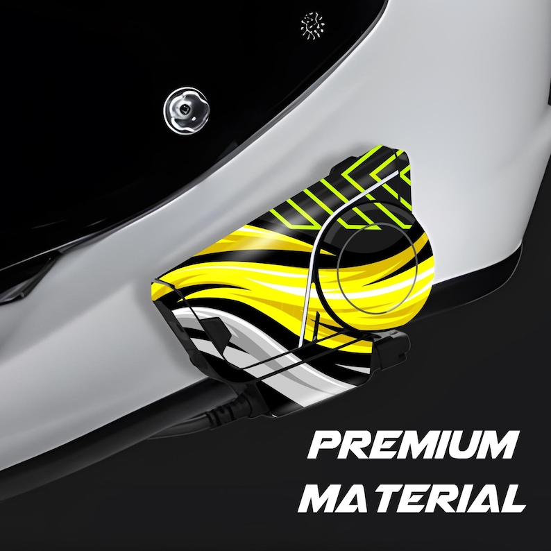 May include: Close-up of a black and white object with a yellow and black design. The text "PREMIUM MATERIAL" is printed in white. The object is attached to a white surface.