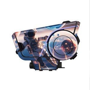 May include: A black and white device with a space-themed graphic of an astronaut floating in space. The device has a circular design element and a purple light. The background features planets and stars.