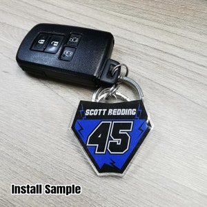 May include: A blue and black key chain with the text "SCOTT REDDING 45" on it. The keychain is attached to a silver key ring.
