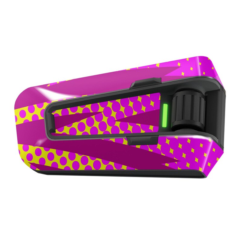 May include: A pink and yellow patterned motorcycle helmet communication device with a black control knob and a green light.