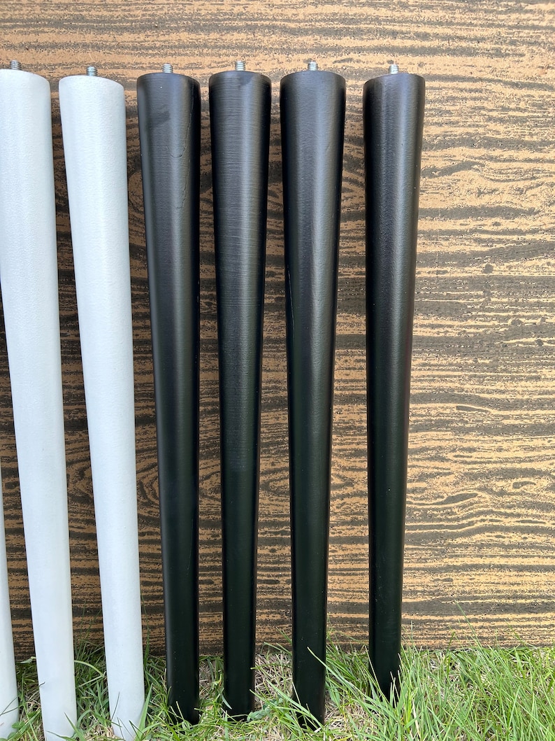 May include: Six wooden furniture legs, four black and two white, arranged in a row. The legs are tapered and have a smooth finish.