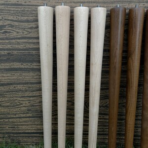 May include: Six wooden table legs, four are light wood and two are dark wood. The legs are all the same size and shape, and they are arranged in a row.