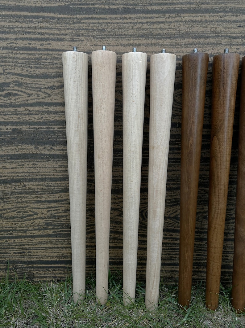 May include: Six wooden table legs, four are light wood and two are dark wood. The legs are all the same size and shape, and they are arranged in a row.