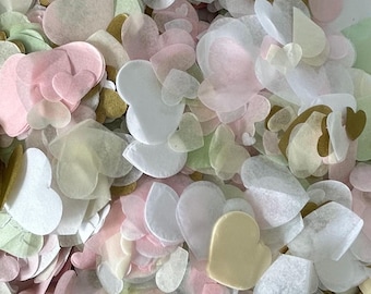 May include: A close-up view of a pile of heart-shaped confetti in various pastel colors. The confetti includes shades of pink, white, green, and gold. The confetti is made of a thin, translucent material.