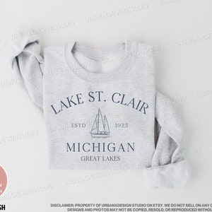 May include: A gray sweatshirt with a navy blue graphic design featuring a sailboat and the text "Lake St. Clair Est. 1925 Michigan Great Lakes".