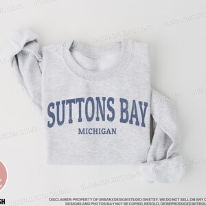 May include: A gray sweatshirt with the text "Suttons Bay, Michigan" printed in blue.