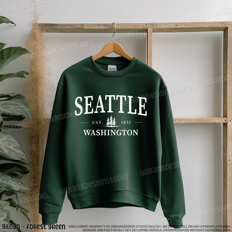 May include: Forest green sweatshirt with white text that reads "Seattle Est. 1851 Washington" with a small graphic of pine trees.