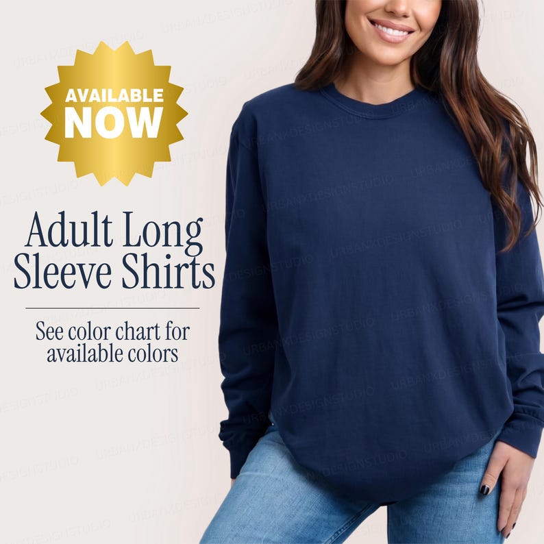 Puede incluir: Una camiseta de manga larga de color azul marino s&oacute;lido con cuello redondo. La imagen incluye un gr&aacute;fico de estrella dorada con el texto AVAILABLE NOW, y texto negro que dice Adult Long Sleeve Shirts y See color chart for available colors.