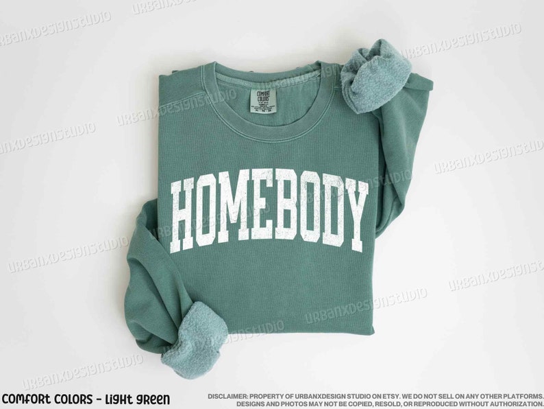 May include: A light green sweatshirt with the word "HOMEBODY" printed in white on the front.