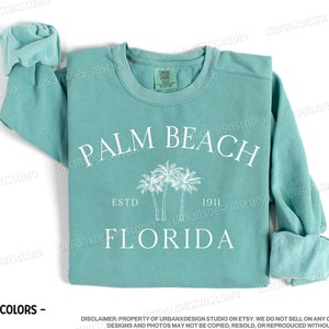 May include: Seafoam green sweatshirt with a white graphic print of palm trees and the text "PALM BEACH ESTD 1911 FLORIDA".