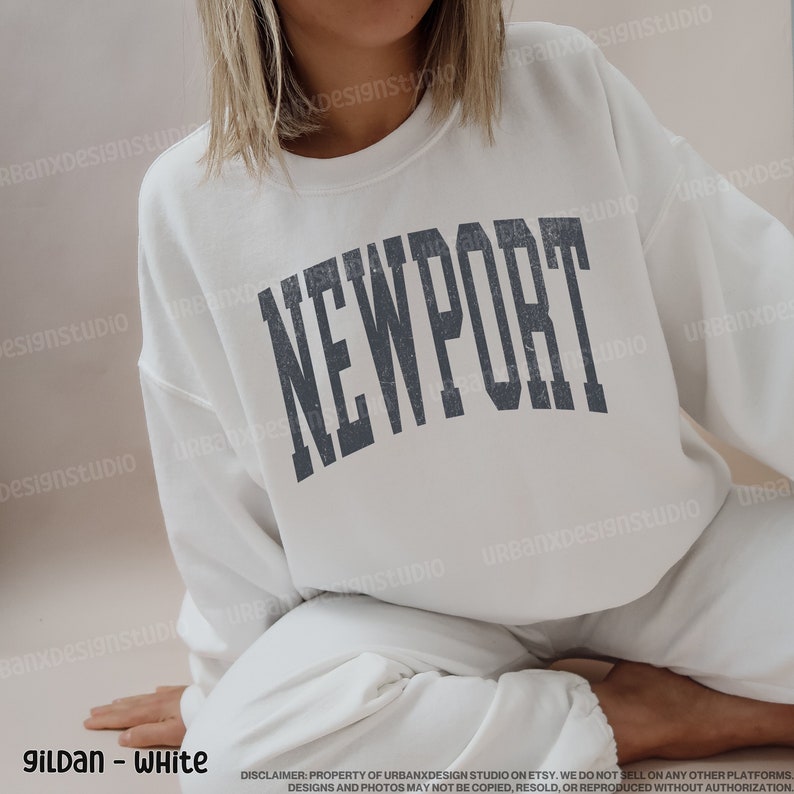 May include: White sweatshirt with the word "NEWPORT" printed in a dark gray, distressed font.