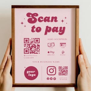 Könnte beinhalten: Ein rosa-weißes Schild mit dem Text "Scan to pay" in einer Retro-Schriftart. Das Schild enthält einen QR-Code, einen Firmennamen und Logos für CashApp, Apple Pay und PayPal. Das Schild enthält auch Social-Media-Icons für Facebook, Instagram und eine Website.