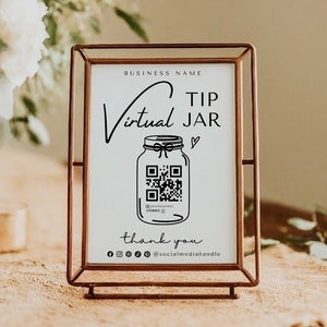 May include: A white sign with black text and a QR code in a copper frame. The sign reads "Virtual Tip Jar" with a jar icon and a heart. The text also includes "Thank you" and social media icons.