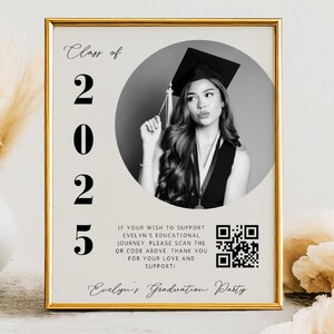 May include: A framed graduation announcement with a gold border. The announcement features a black and white photo of a graduate wearing a cap and gown. Text includes "Class of 2025" and a QR code.