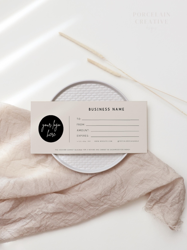 Op de afbeelding: Een beige cadeaubon met zwarte tekst. De tekst luidt "BUSINESS NAME", "TO", "FROM", "AMOUNT", "EXPIRES", "WWW.WEBSITE.COM" en "@SOCIALMEDIANHANDLE". Een zwarte cirkel met de tekst "your logo here" bevindt zich in de linkerbovenhoek.