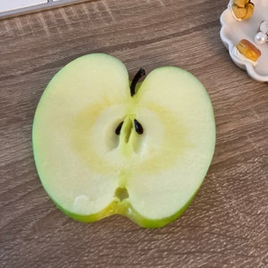 May include: A close-up of a green apple cut in half, showing the core and seeds.
