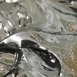 Op de afbeelding: Close-up van een zilveren vloeibaar metaaloppervlak met een rippelende, golvende textuur. Het metaal reflecteert licht, waardoor een glinsterend effect ontstaat.