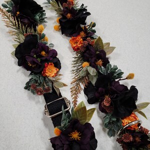 May include: Two black fabric straps with black, purple, and orange floral embellishments. The straps have silver metal buckles.