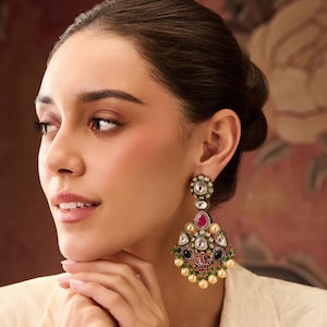 Könnte beinhalten: Ein Paar goldene Ohrringe mit einem tropfenförmigen Mittelstück, das von kleineren Steinen umgeben ist. Die Ohrringe sind mit Perlen und grünen und blauen Steinen verziert.