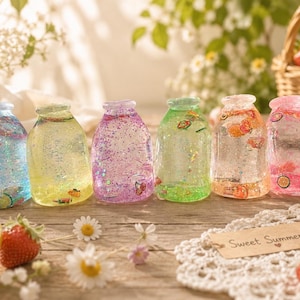 May include: Six small, clear glass bottles filled with colorful, glittery liquid and miniature fruit-shaped charms. The bottles feature blue, yellow, purple, green, orange, and pink hues. A small brown tag with the text Sweet Summer is present.