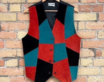 Könnte beinhalten: Eine Vintage-Patchwork-Weste in einem auffälligen Colorblock-Design. Die Weste hat Einsätze aus rotem, blaugrünem und schwarzem Wildleder mit einem schwarzen Samtrücken und Revers. Sie hat eine Knopfleiste und hängt an einem Holzbügel.