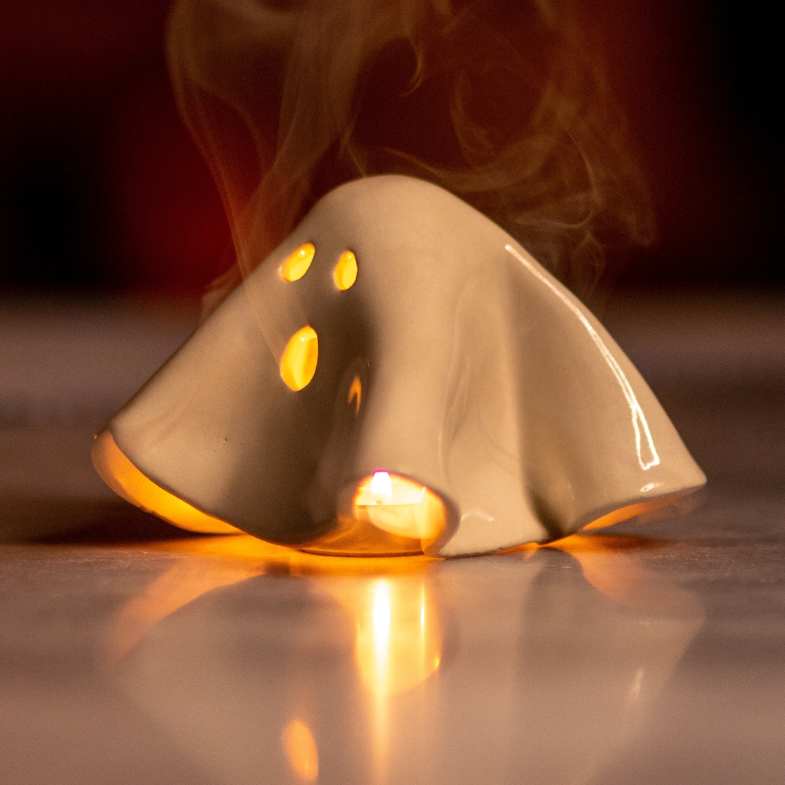 A white ceramic incense holder, molded to look like a halloween ghost.