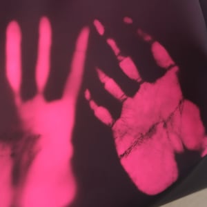 以下が含まれることがあります： 暗い表面に2つのピンク色の手形。手形は熱によって見えます。