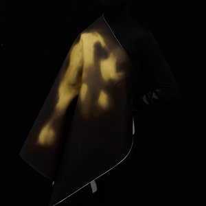 Może przedstawiać: Czarny odzież z żółtym wzorem farby w sprayu. Odzież jest zarzucona na ramię osoby.