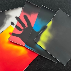Puede incluir: Cinco cuadrados de papel negro sensibles al calor, cada uno mostrando un color diferente cuando se toca. Los colores son rojo, amarillo, azul y blanco.