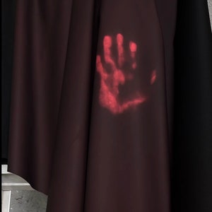 May include: A close-up of a dark red fabric with a faint red handprint on it.
