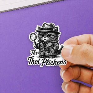 May include: A black and white sticker featuring a cartoon cat detective wearing a fedora and trench coat, holding a magnifying glass. The text "The Thot Plickens" is below the cat.