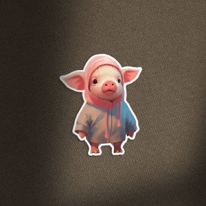 May include: A pink pig wearing a blue hooded jacket. The pig has a pink nose and is looking to the left.