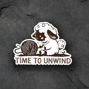 May include: A white sheep with black eyes and a brown yarn ball is holding a string of yarn. The text "TIME TO UNWIND" is below the sheep.