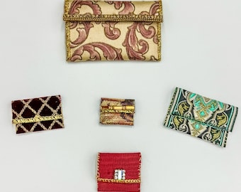 May include: Five small fabric purses in different colors and patterns. The purses are all closed and have a gold trim.