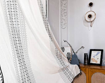May include: White curtain with black embroidered geometric patterns and tassels along the edges. The curtain is hanging in front of a light-colored wall. The curtain is part of a home decor collection.